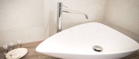 Un baño con lavamanos blanco, un grifo moderno y una encimera de madera.