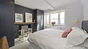 Une chambre avec un grand lit, une chaise, une cheminée et des œuvres d’art accrochées au mur.