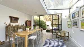 Un coin repas avec une table en bois, des chaises transparentes et un tapis à carreaux.