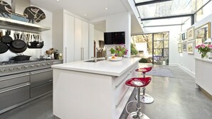 Une cuisine moderne dotée d’appareils électroménagers en acier inoxydable, d’un grand îlot central et de tabourets de bar rouges.