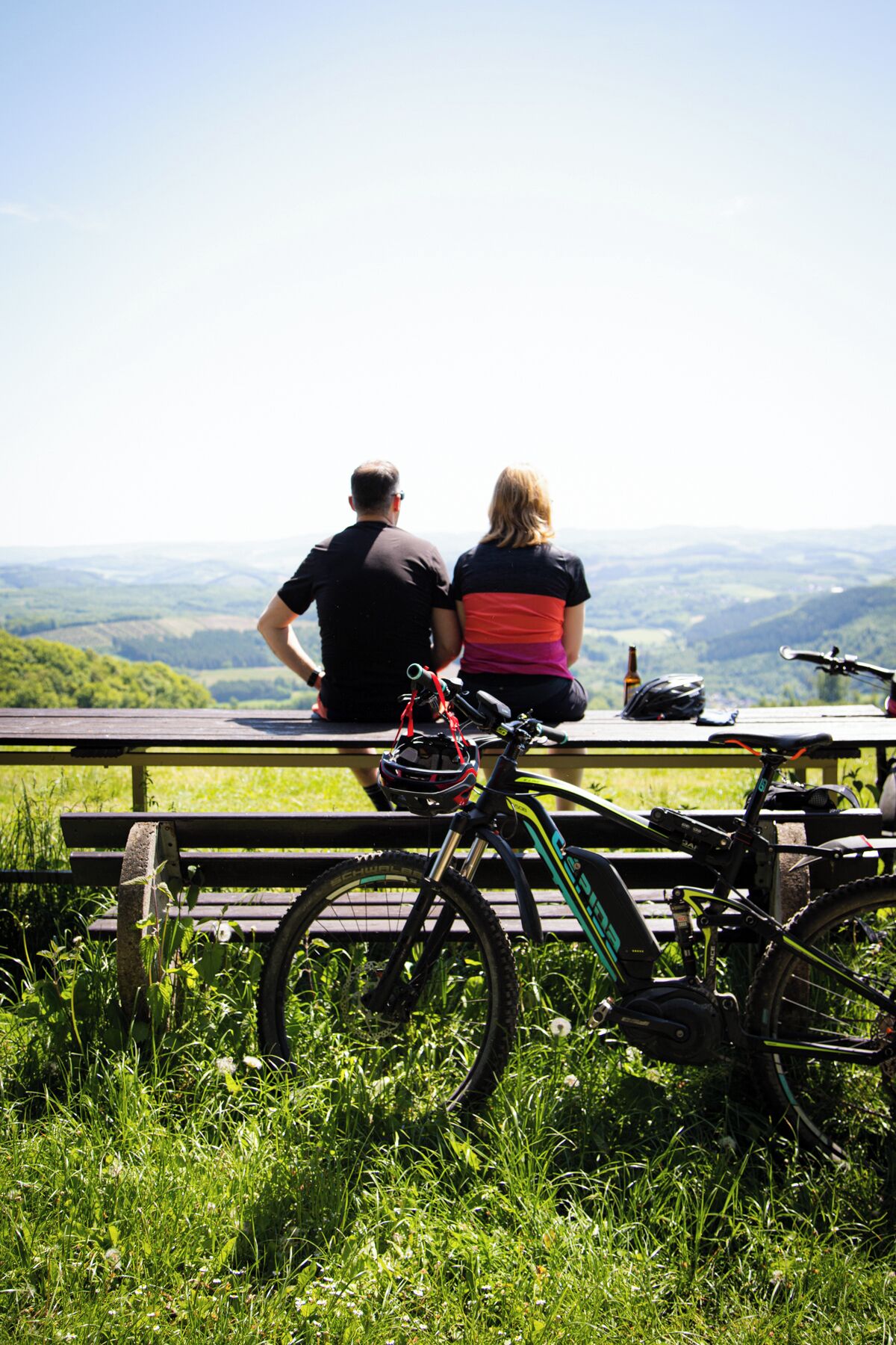 A couple sitting on a bench overlooking a scenic view.
