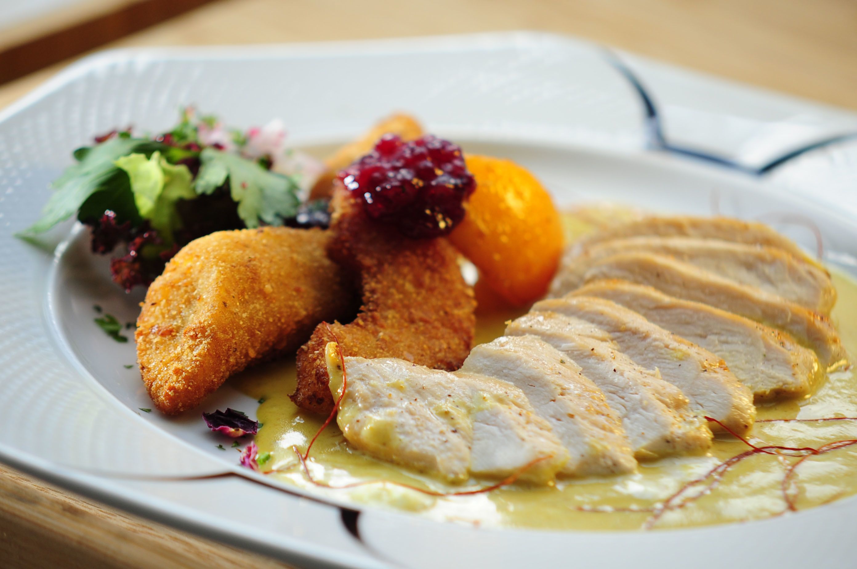 Ein Teller mit paniertem Hähnchen, Obst und einem gemischten Salat.