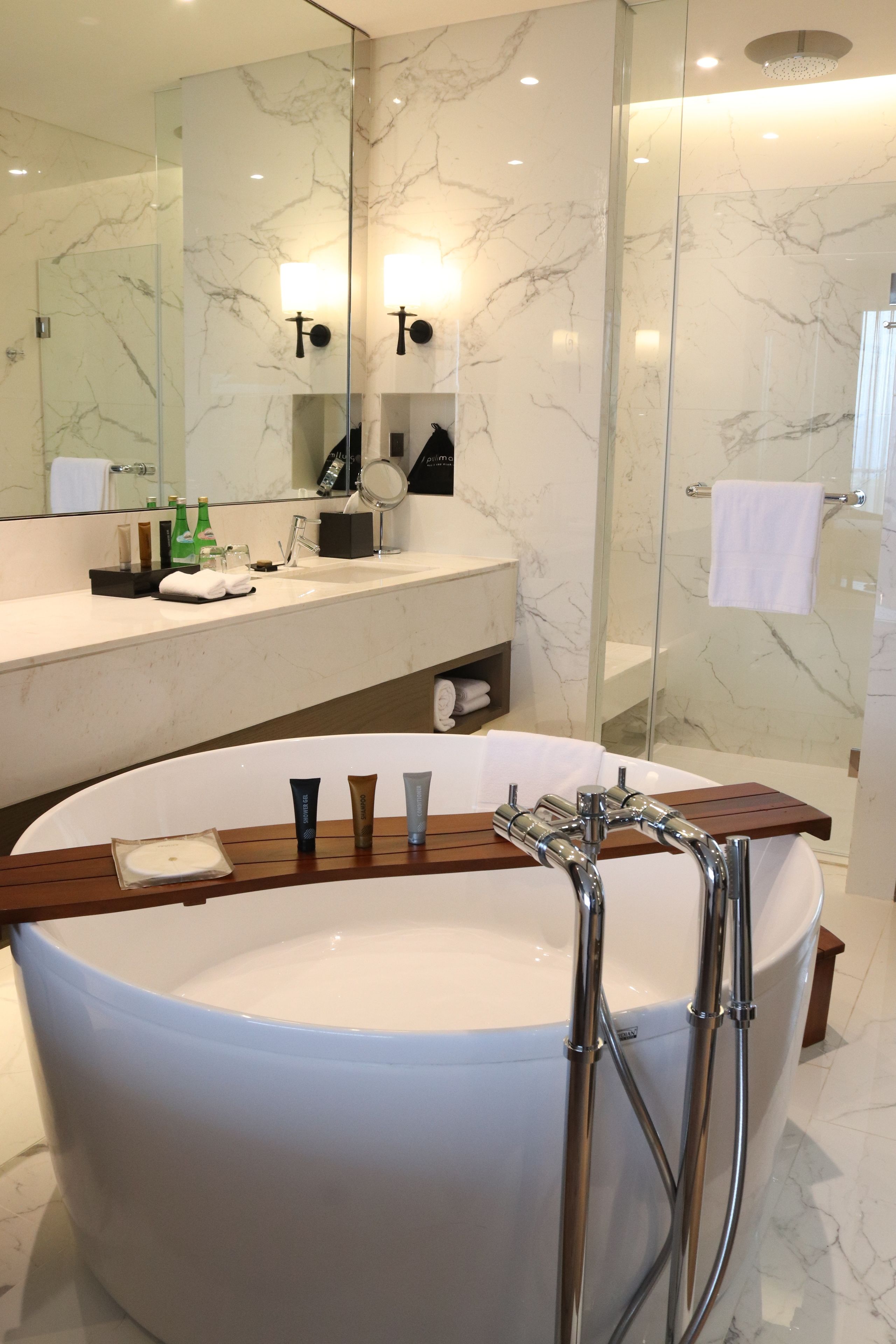 A modern bathroom with a large bathtub, a wooden vanity, and a glass-enclosed shower area.