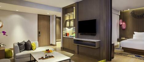 A modern hotel room with a flat-screen TV, a sofa, a dining table, and a bed.