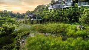Een modern resort met meerdere gebouwen, weelderige begroeiing en een vijver met lotusbloemen.