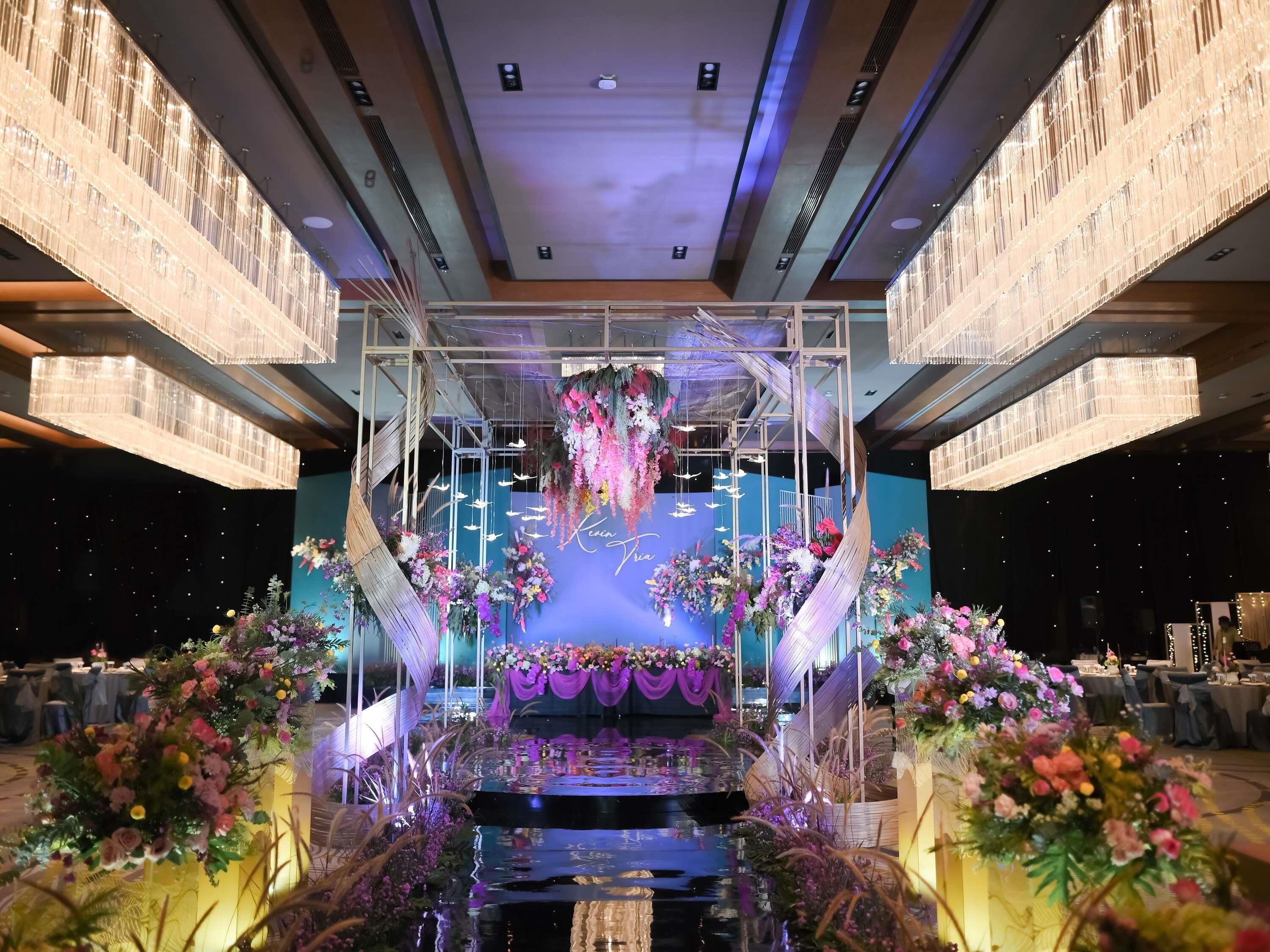 A reception area with a central stage, floral arrangements, and a blue wall with a neon sign.