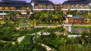 Een hotel met meerdere verdiepingen, een zwembad en weelderige beplanting.