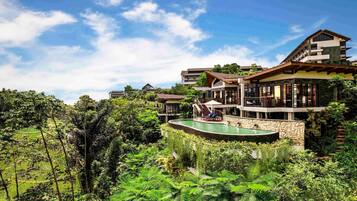 A multi-story resort with a pool surrounded by lush greenery.
