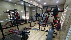 A gym with exercise equipment, a mirror, and a wooden floor. - Degok Hotel (Abuja)