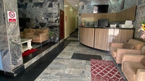A hotel lobby with marble walls, a reception desk, seating area, and a no-smoking sign. - Degok Hotel (Abuja)