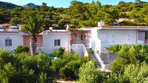 A residential area with houses featuring red-tiled roofs and white walls, surrounded by lush greenery and hills in the background. - The Blue Moon Apartment "Iris Blu", sea view, 500 meters from the beach (Ferma)