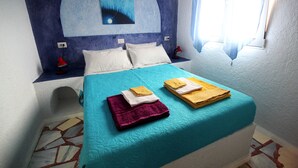 A bed with a teal bedspread, two pillows, and two folded towels on top. - The Blue Moon Apartment "Iris Blu", sea view, 500 meters from the beach (Ferma)