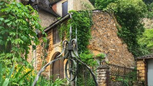 Un edificio rústico de piedra con techo de tejas tradicionales, pared de piedra y puerta de metal.