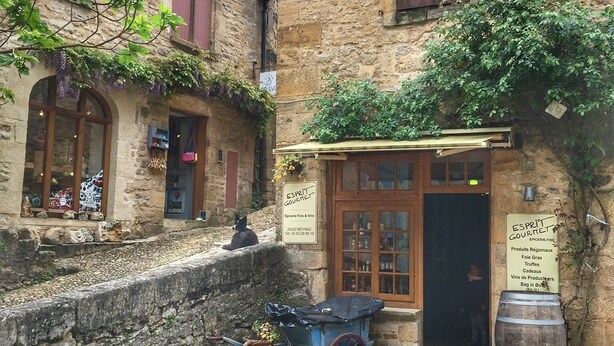 Un edificio de piedra con un letrero que dice 'ESPRIT GOURMET' y un pequeño carrito afuera.