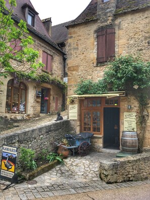 A stone building with a sign for 'ESPRIT GOURMET' and a small cart outside.