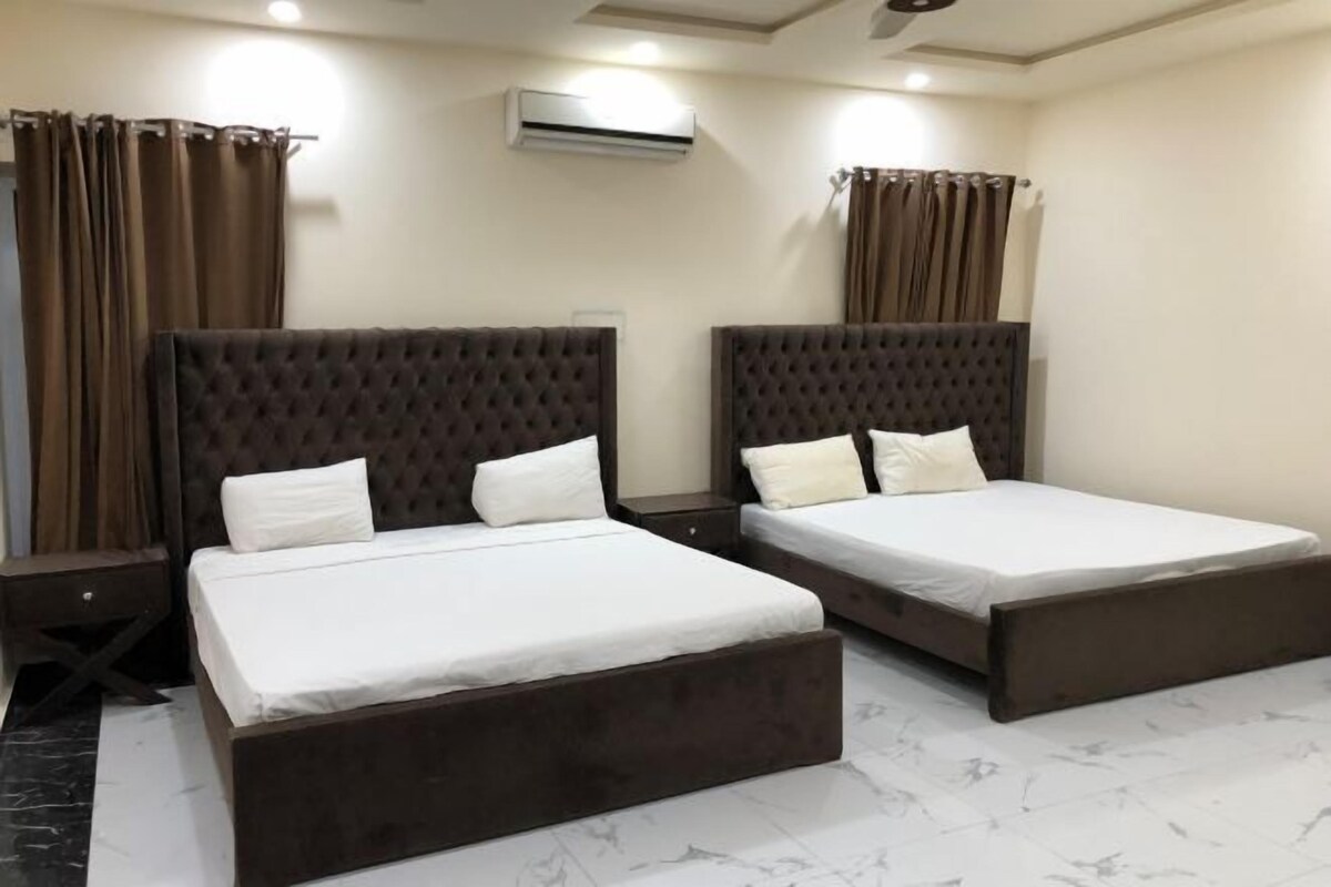 A hotel room with two beds, brown headboards, white bedding, and a marble floor.