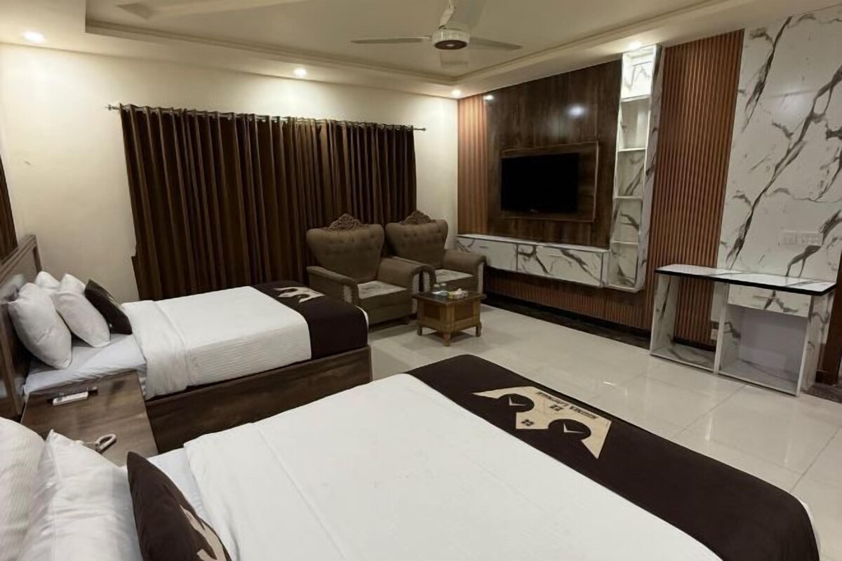 A hotel room with two beds, a TV, a desk, and a ceiling fan.