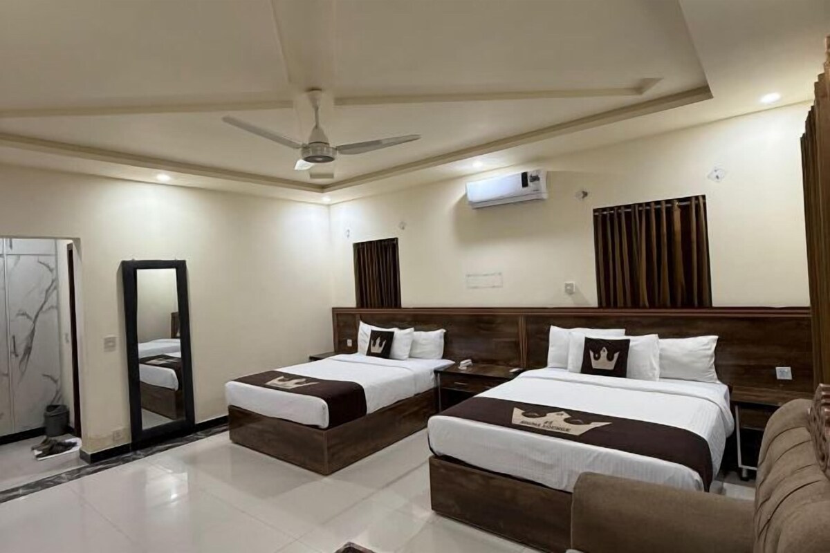 A hotel room with two beds, a ceiling fan, an air conditioning unit, and a mirror.