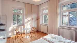 A bedroom with a bed, two chairs, a small table, and large windows. - Die Burg Schöna - In a national park (Reinhardtsdorf-Schoena)