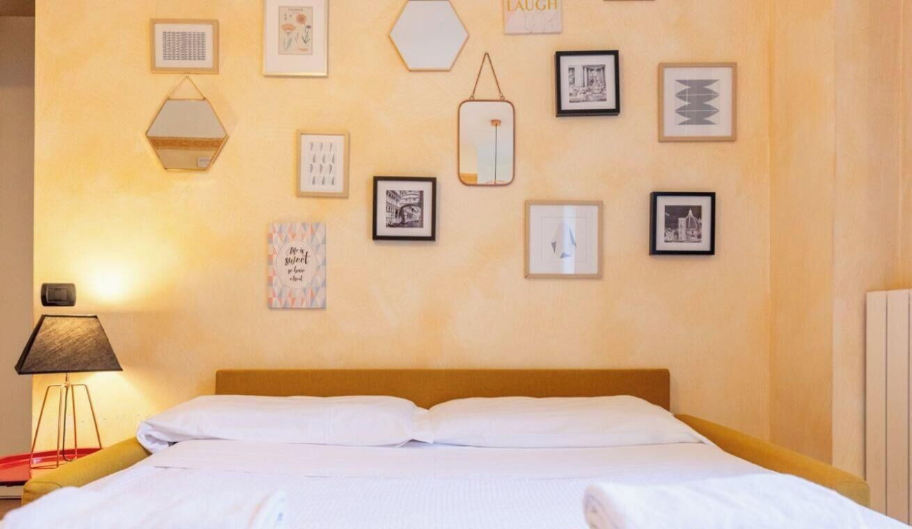 Une chambre d’hôtel avec un lit, une lampe de chevet et un mur décoré de divers tableaux encadrés.