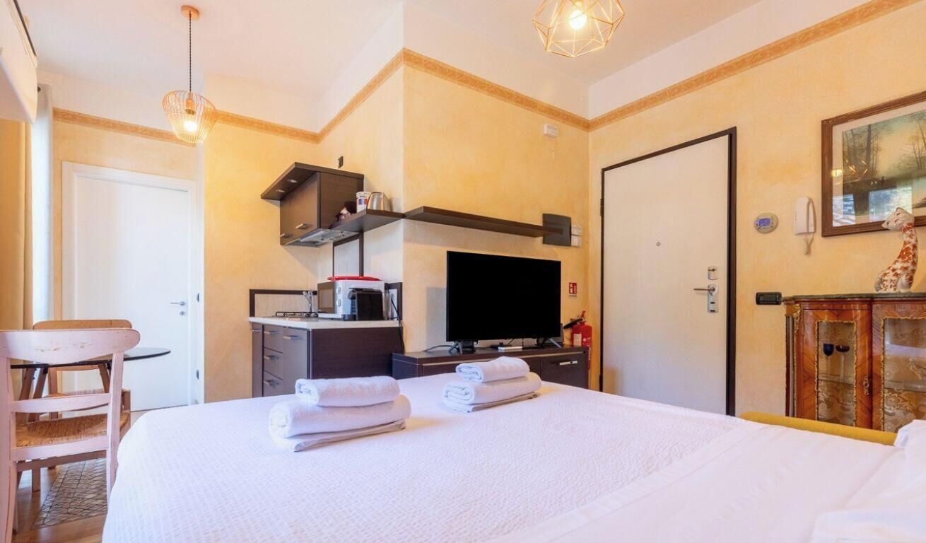 A hotel room with a bed, a desk, a television, and a minibar.