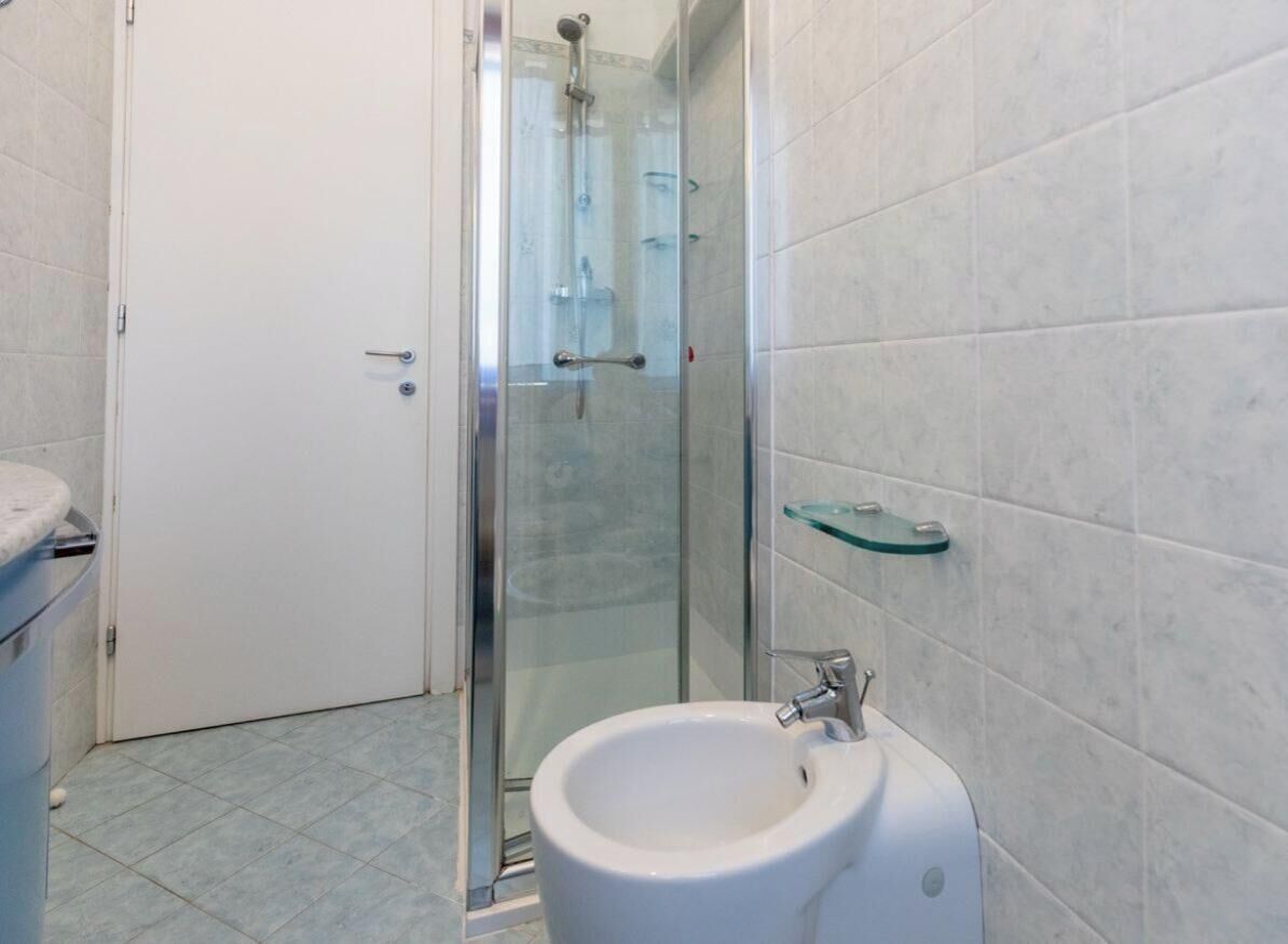 Un baño con cabina de ducha de vidrio, un bidé y una repisa de vidrio.