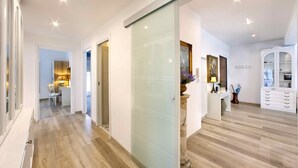 Un intérieur moderne avec un plancher en bois, une cloison en verre, un bureau avec une lampe et un meuble avec des tiroirs.