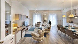 Un salon moderne comprenant un canapé, des fauteuils, une table à manger et un téléviseur.