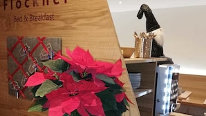 Un mostrador de recepción de madera con una planta en maceta, una máquina de café y un objeto decorativo.