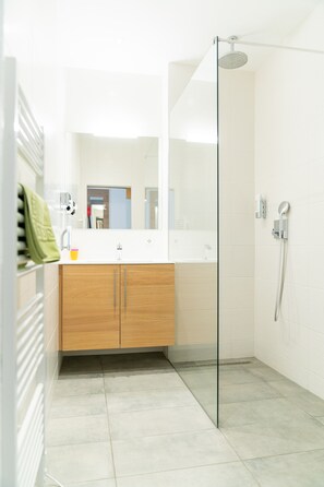 A modern bathroom with a glass shower enclosure, a wooden vanity, and a large mirror. - Flöckner B & B (Salzburg)