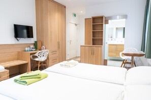 A hotel room with a bed, a desk, a chair, a TV, and a wardrobe. - Flöckner B & B (Salzburg)