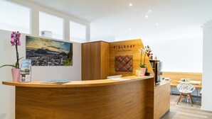Una recepción con detalles de madera, un cuadro de un paisaje urbano y un cartel que dice "Flockner Bed & Breakfast".