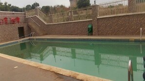 Una piscina con pared de piedra y barandilla de metal.