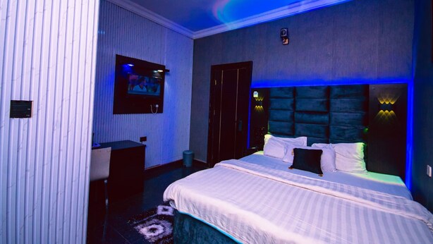 Una habitación de hotel moderna con una cama grande, un escritorio y una televisión en la pared.