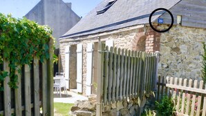 A stone building with a wooden fence, a gravel path, and a stone wall.