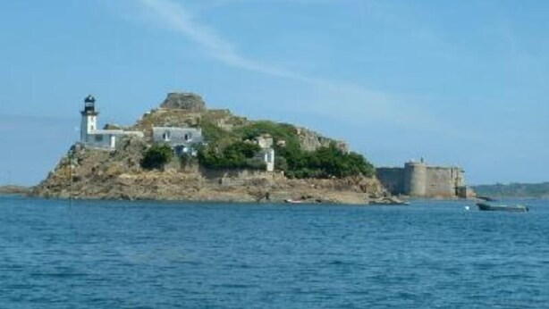 A coastal fort with a lighthouse and multiple buildings on a rocky island.