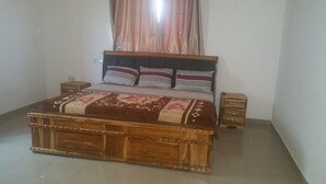 A bedroom with a wooden bed, a bedside table, and a nightstand. - Permiss Ka Apartments (Accra)