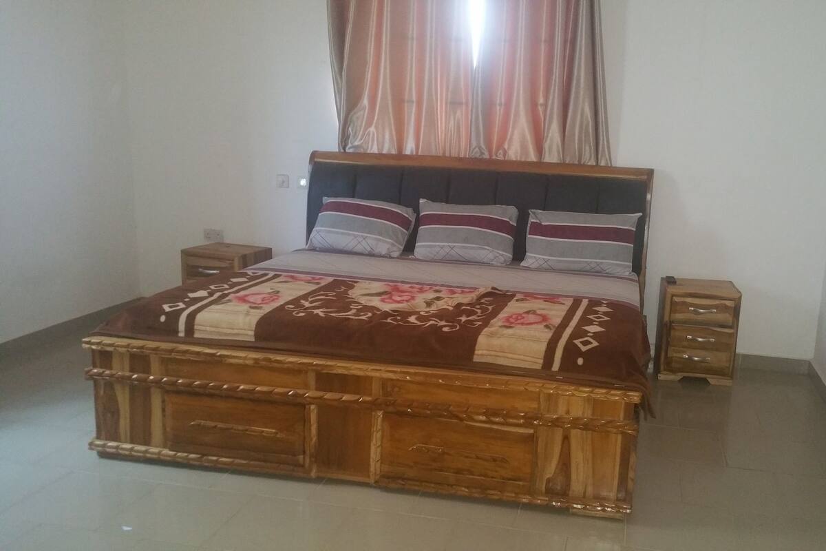 A bedroom with a wooden bed, a bedside table, and a nightstand.