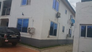 A building with multiple windows, an air conditioning unit, and a satellite dish. - Permiss Ka Apartments (Accra)