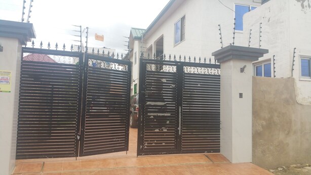 A gated entrance to a building with a tiled driveway. - Permiss Ka Apartments (Accra)