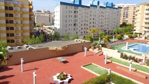 Eine Dachterrasse mit Pool, Grünflächen und Blick auf die umliegenden Gebäude.