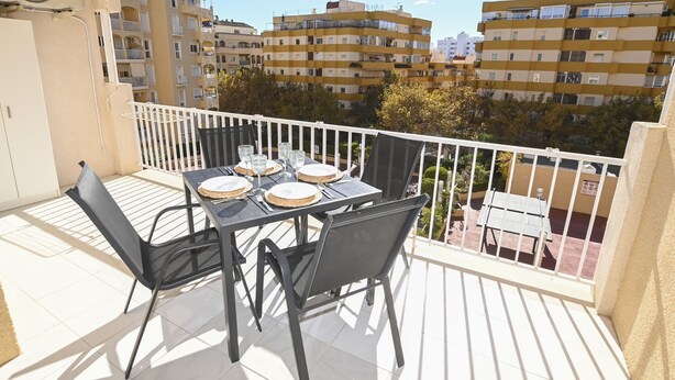 Ein Balkon mit einem Tisch für vier Personen, Stühlen und einem gelben Markisen