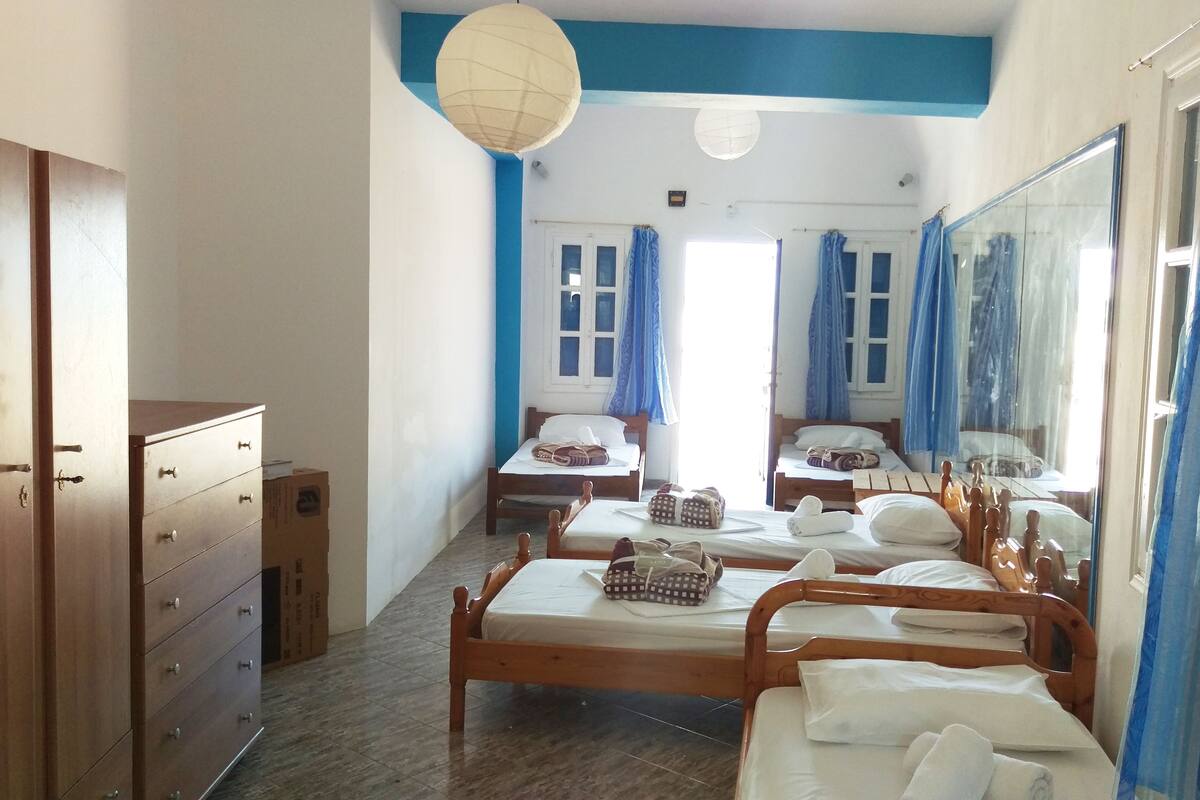 A hotel room with two wooden beds, a wardrobe, a mirror, and a ceiling light fixture.