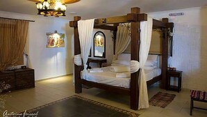 A four-poster bed with a canopy, a chandelier, a mirror, and a small bedside table. - Dodo's Santorini (Santorini)