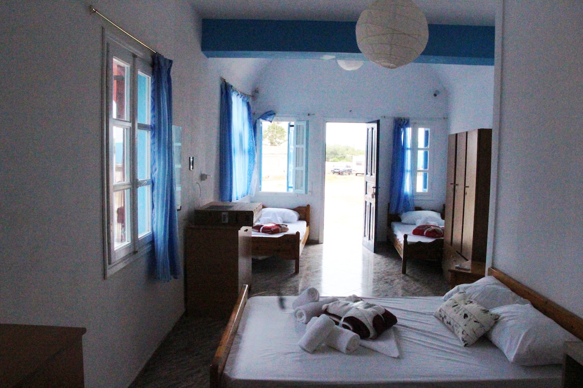 A hotel room with a bed, a desk, and a wardrobe. There are two beds in the room.