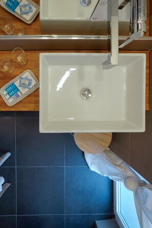 Un baño con lavamanos blanco, un espejo y una ventana con cortina.