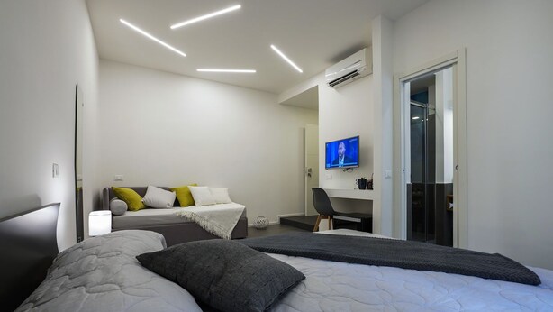 Une chambre d’hôtel moderne, dotée d’un grand lit, d’un bureau et d’une télévision.