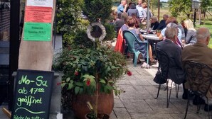 Un espace extérieur aménagé avec des tables et des chaises, entouré de verdure et de plantes en pot.