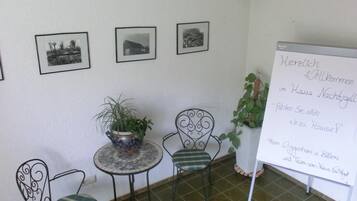 Una habitación pequeña con una pizarra, dos sillas, una mesa y tres cuadros en la pared.