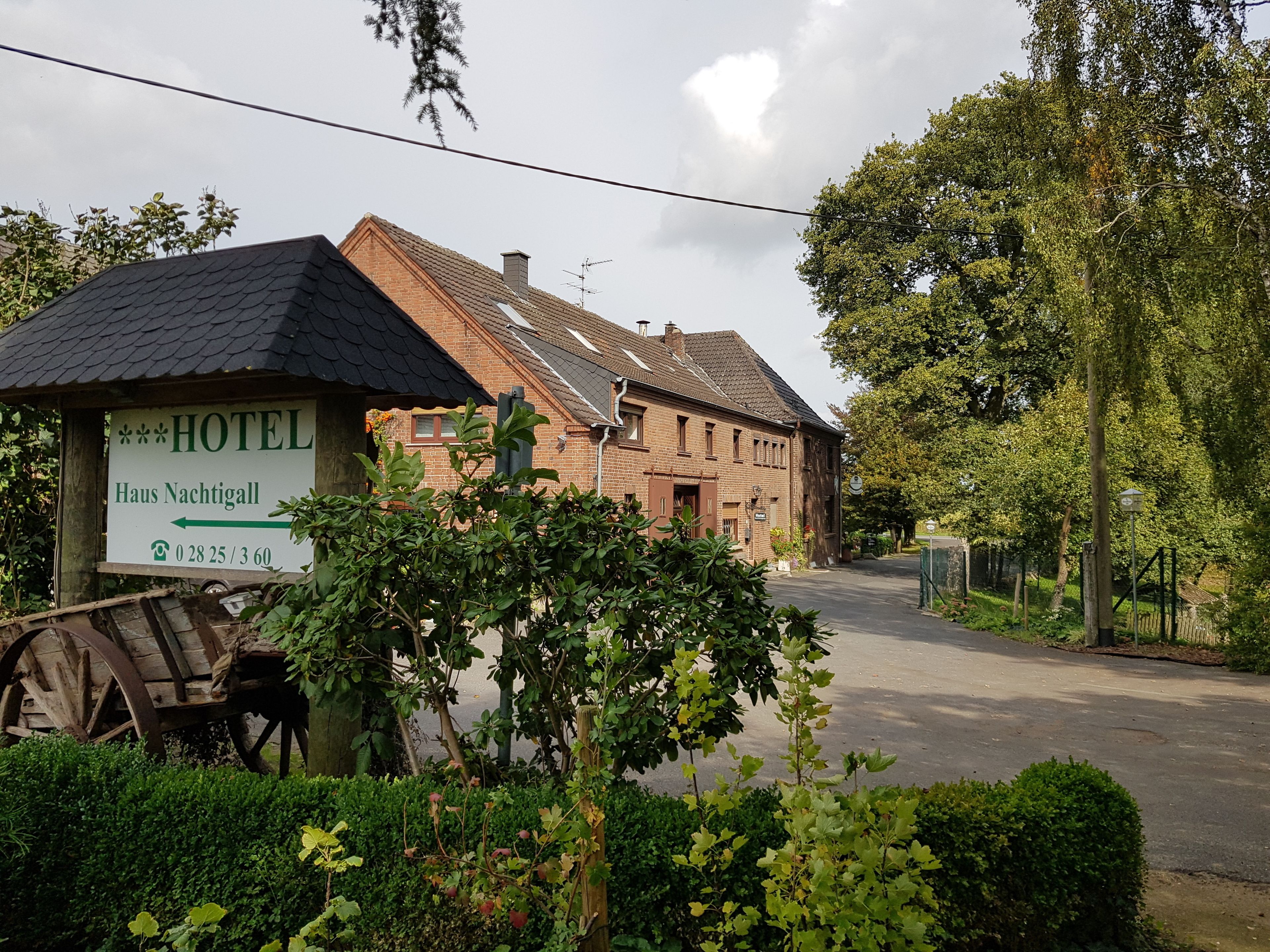 A traditional brick building with a sign indicating it is a hotel named "Haus Nachtigall."